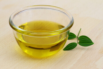 Healthy olive oil in transparent glass bowl on wooden surface
