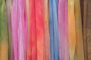 Colourful scarves hanging from a stall in a market in Europe