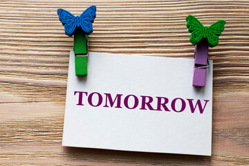 TOMORROW - word on a white sheet with beautiful clothespins on a wooden background