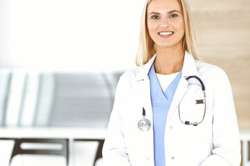 Woman-doctor at work in clinic happy of her profession. Blond female physician controls medication history record and medical exam results. Medicine concept