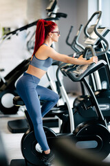 Fototapeta na wymiar active woman in the gym, working out and smiling on stationary bicycle at gym. Fitness and bodybuilding concept