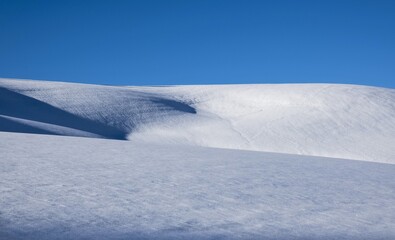 Sunny day in winter. Snowy hills and blue sky