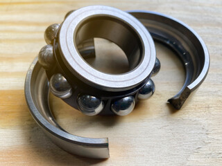 Closeup metal ball bearing on wooden background, dismantle or bearing cut inside for check...