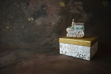 Christmas or New Year background. Glitter train toy on gift box on dark background
