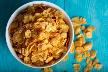 Bowl with tasty corn flakes on wooden table. Top view.
