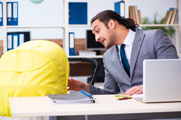 Young male employee looking after newborn at workplace