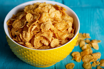 Bowl with tasty corn flakes on wooden table. Top view.