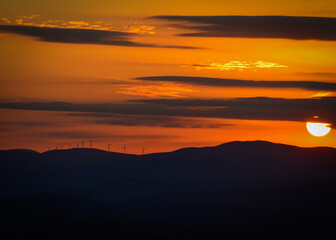 Obraz premium Orange sky with mountain and wind turbing horizon Mount Olga Wilmington Vermont Nov. 2020