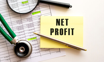 NET PROFIT text on a sticker on your desktop. Pen and magnifier.