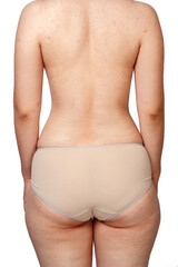 young woman in beige panties . rear view . buttocks with cellulite and overweight. on a white...