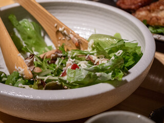 Seasoned green salad in a bowl with wooden cutlery