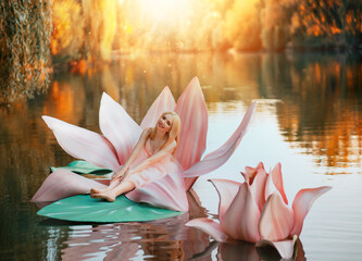 Happy fantasy young blonde woman little fairy princess sitting in pink lotus flower on lake water....
