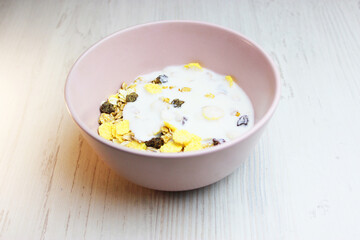 muesli with on a pink plate, top view. Muesli with fresh milk, yogurt or kefir. Muesli is made from oatmeal, a mixture of multi-grain flakes with dried fruits, nuts and sunflower seeds. on a white