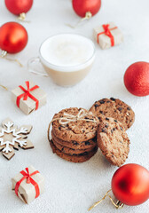 Cookie with chocolate and coffe on the white background. New Year's decorations and gift boxes surround them.