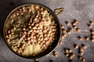 Chickpea flour and chickpea kernels in the old metal bowl.
