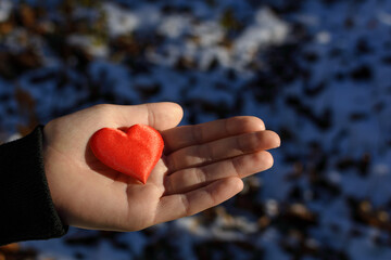 female hand holding red heart in winter time
