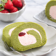 Delicious Matcha Swiss Roll Cake slices with strawberry cream on white background.