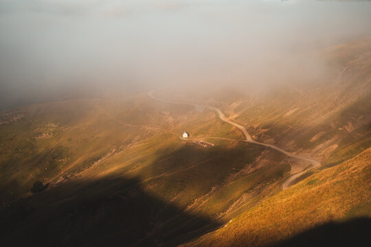 Small cabin beneath the fog next to a gravel path