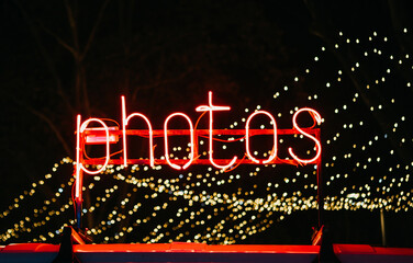 Photos neon sign at night. In the background garlands.