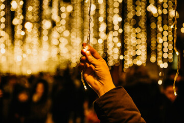 A girl holds a New Year or Christmas garland in her hands during the holiday. Christmas lights in...