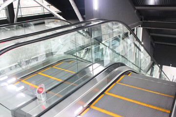Obraz premium Modern luxury escalators with staircase in a shopping mall Metal excavator with neon lighting with rubber handrails, staircase view, descent to the floor .. Awareness of safety in daily life Modern