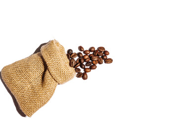 Roasted coffee beans scattered from burlap bag isolated on white background. Copy space.