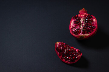 Fototapeta premium Pomegranate on a black background. Cut Pomegranate. Red fruit. Photo from above. There is a place for an inscription or logo