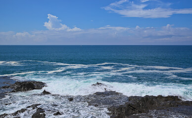 View of the ocean on a partly cloudy day from a rocky shoreline on Enoshima Island