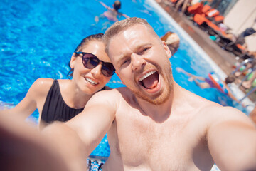 Couple happy caucasian beautiful young woman and man make selfie photo on background swimming pool. Concept travel summer trip