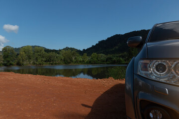 Headlights of a gray car parked on the red ground And there are reservoirs and mountains in the scene. View of Salak Pet Koh Change Trat Thailand.