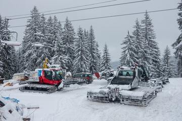 Snow ploughs with caterpillar tracks are parked up in a european ski resort having been out...