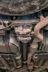 Car lifted in automobile service for fixing, worker repairs detail, telephoto. Car maintenance shop. Lifted chassis car for repairing under the car in garage shop. vertical photo. toned