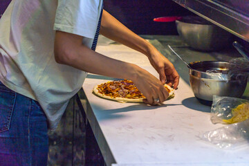 Baker preparing pizza dough at kitchen bar in restaurant