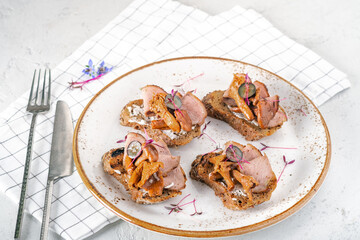 Traditional Scandinavian open sandwich with chanterelle mushrooms, cream cheese and ham on white plate