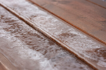 Background of the veranda floor of brown planks covered with ice
