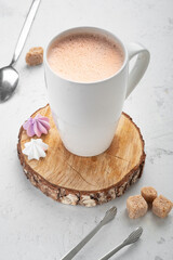 Cocoa with foam in a white mug with sweets on a white table, hot chocolat on breakfast