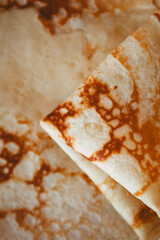 Traditional homemade thin pancakes without syrup, honey or jam on the white plate on the stone table. Close-up of prepared food. Fried or baked pastry for breakfast. Milan, Lombardy, Italy.