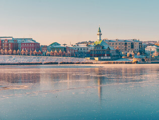 Fototapeta premium Old Tatar district at sunrise in winter. Reflection in the ice of a frozen river. Beautiful view of the city. Lake Kaban and mosques