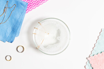 Cleaning jewelry at home. Golden jewelry and cleaning tools on white table. Top view
