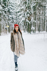 Young attractive hipster girl walking in the snow forest
