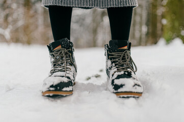 Cropped woman legs in boots standing in the snow