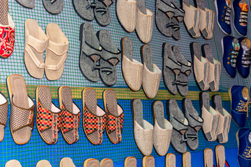Rows of traditional colorful flip flop and slipper sandals are displayed for sale.