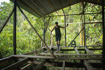 Hombre joven haciendo equilibrio en una construcción de una casa en medio de la naturaleza
