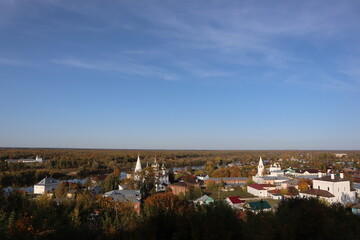 Fototapeta na wymiar Beautiful autumn panorama, landscape, top view, Vladimir city, Russia. Stunning autumn landscape, top view, sun and blue sky, yellow trees, white Church, Golden domes, green grass, red leaves. Park. 