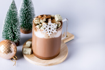 Glass Cup of Hot Cocoa with Homemade Marshmallows on Wooden Tray Light Blue Background Fake Christmas Tree Holiday Morning or Breakfast Horizontal Copy Space