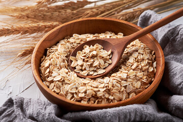 Rolled oats or oat flakes in bowl with wooden spoon background