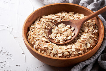 Rolled oats or oat flakes in bowl with wooden spoon background