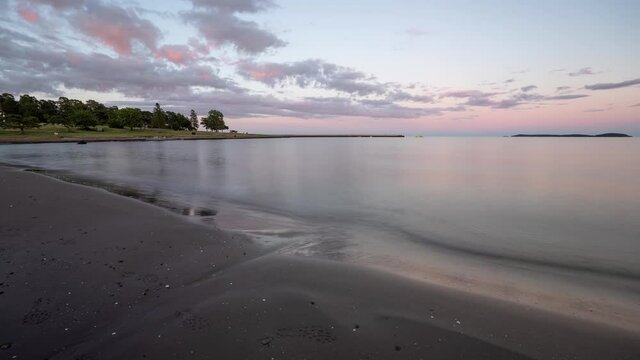 A beautiful sand beach with calmly moving water at sunset time. Southern Norway, time lapse  video