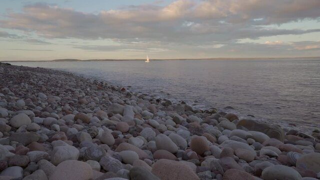 Relaxing video of rocky beach at sunset time. A yacht in the far. Southern Norway