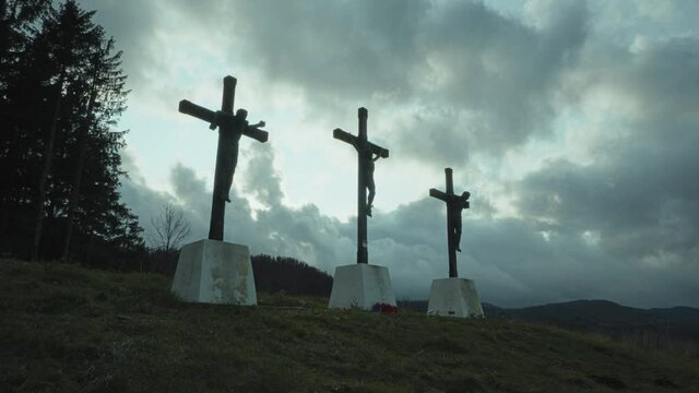 Streaming storm clouds passing behind 3 statues representing the crucifixion of Jesus Christ